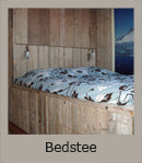 Tweepersoonsbed van steigerhout met ingebouwde lades en verlichting. Ter plaatse gemaakt in een zomerwoning (220x187x227 cm).